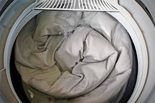 A front-loading washing machine filled with a large body pillow