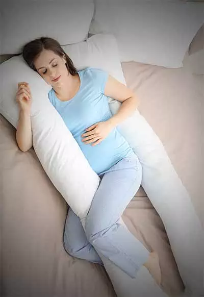 pregnant woman sleeping in a u-shape body pillow