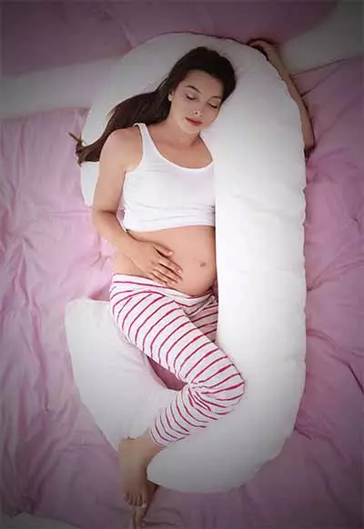 pregnant woman sleeping in a c-shape body pillow